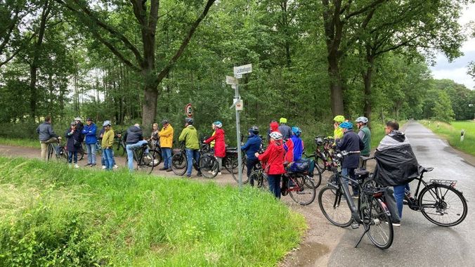 Gruppe von Radfahrern macht Pause am Wegesrand in grüner Natur.